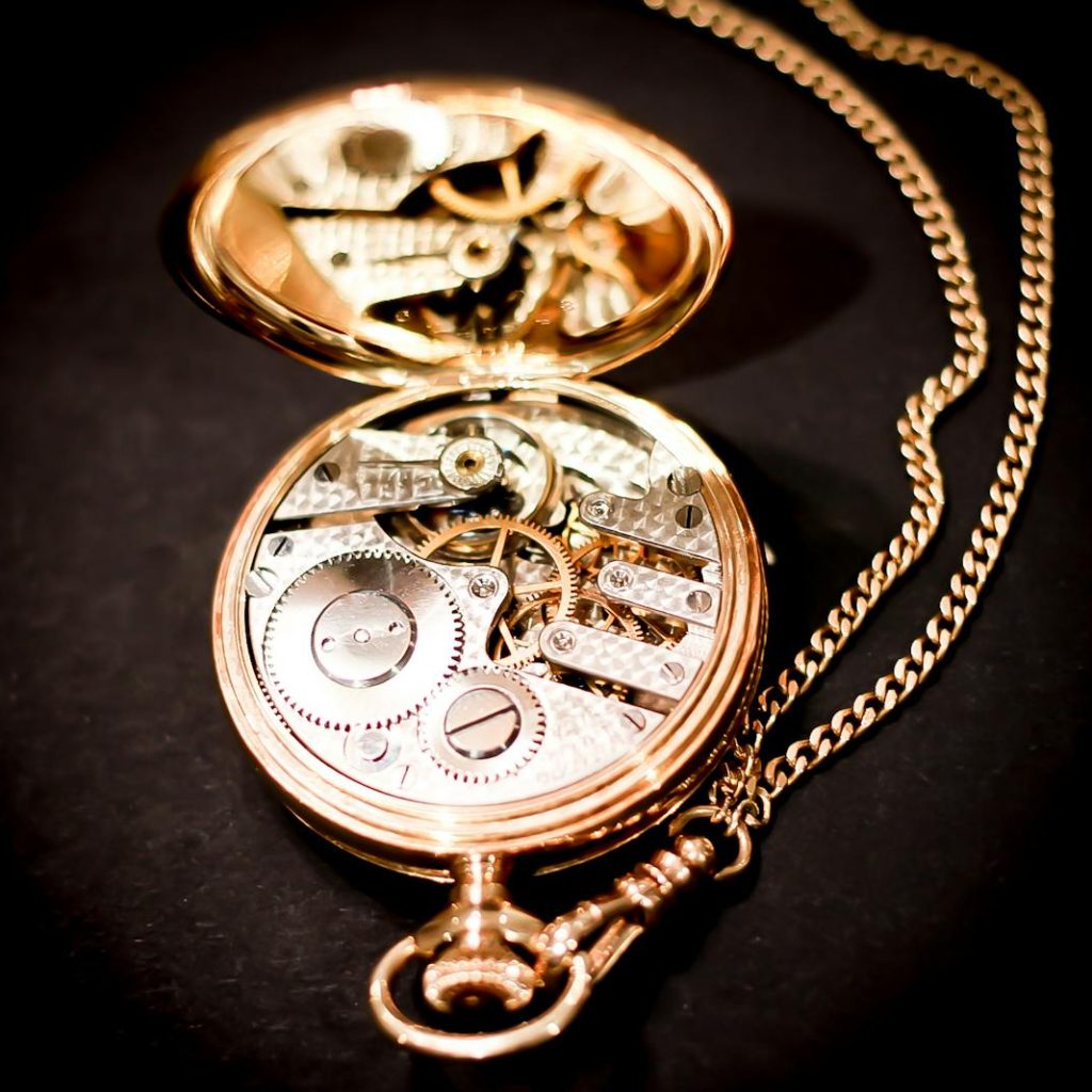 Close-up of an open gold pocket watch revealing its intricate mechanical gears.